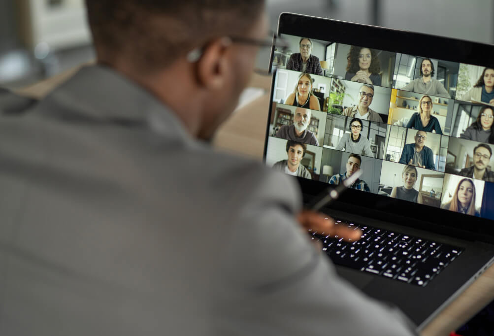 Photo of a man talking to his colleagues on a video conference on his laptop.